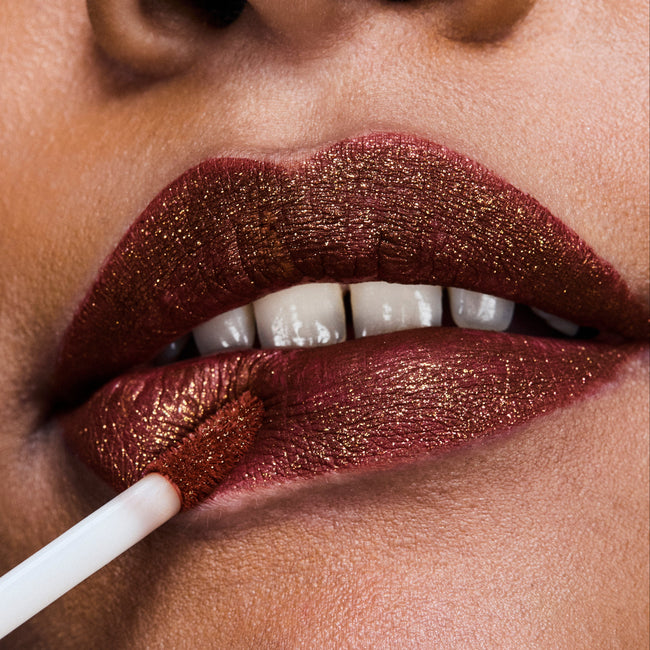 A close-up portrait of a woman's lips wearing Power Stay Spark Liquid Lip Colour in a dark brown metallic matte shade.