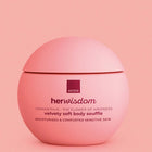 A pink round jar of Avon Her Wisdom Velvety Soft Body Souffle moisturizer, shown against a matching pink background.